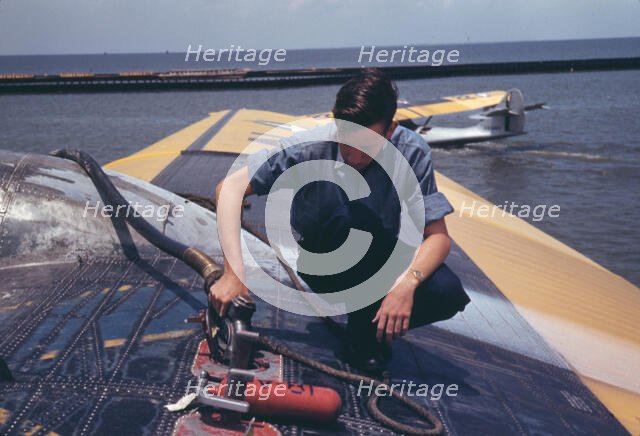 A sailor mechanic refueling a plane at the Naval Air Base, Corpus Christi, Texas, 1942. Creator: Howard Hollem.
