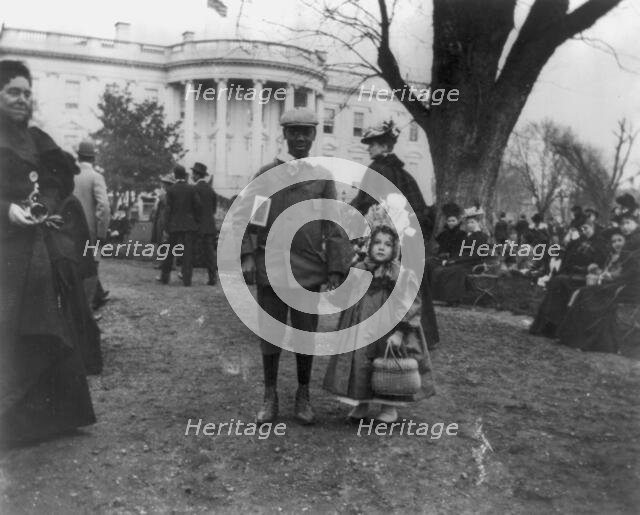 D.C. Wash. - White House - Negro boy holding hand of small white girl during Easter egg roll, 1898. Creator: Frances Benjamin Johnston.