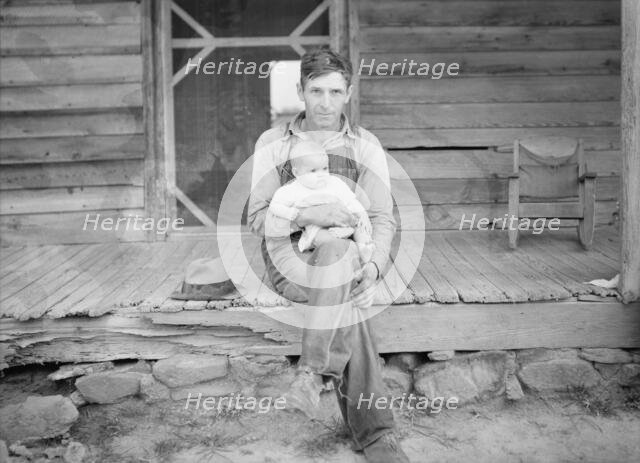 Mr. Whitfield, tobacco sharecropper, with baby on front porch, North Carolina, Person County, 1939. Creator: Dorothea Lange.