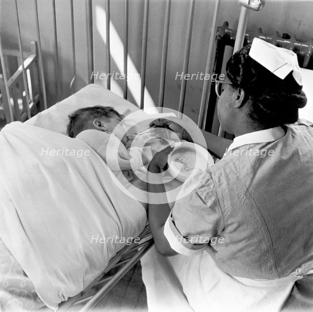 Nurse feeding a child, London, (1960s?). Creator: Henry Grant.
