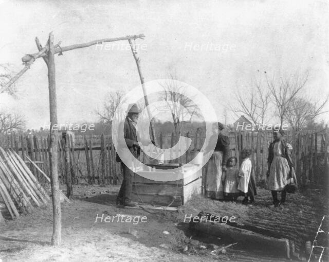 Negro man, woman and three children at an old-time well, 1899 or 1900. Creator: Frances Benjamin Johnston.