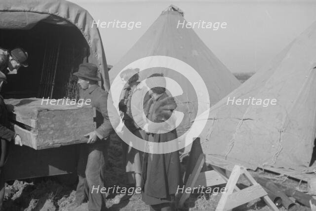 Unloading household goods of a family of white flood refugees in camp, Forrest City, Arkansas, 1937. Creator: Walker Evans.