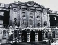 The front entrance of Guy's Hospital, with statues of Aesculapius and Hygieia above the arches. Creator: Unknown.