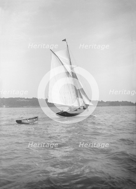 The cutter 'Citara' under sail and towing tender, 1911. Creator: Kirk & Sons of Cowes.