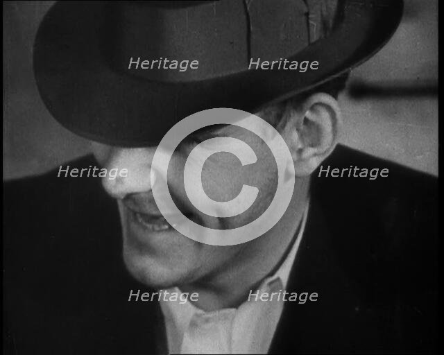 Male American Civilian Wearing a Hat Sitting at a Desk, 1930. Creator: British Pathe Ltd.