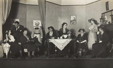 Amateur actors, some in drag, are having tea on stage, [between 1920 and 1929?]. Creator: Unknown.