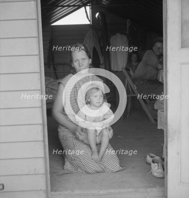 Migrant mother and child at doorway of steel shelter, FSA camp, Tulare County, 1939. Creator: Dorothea Lange.