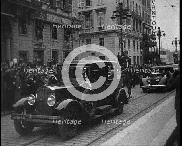 Cars Driving Down a Road, Watched by a Crowd, 1934. Creator: British Pathe Ltd.