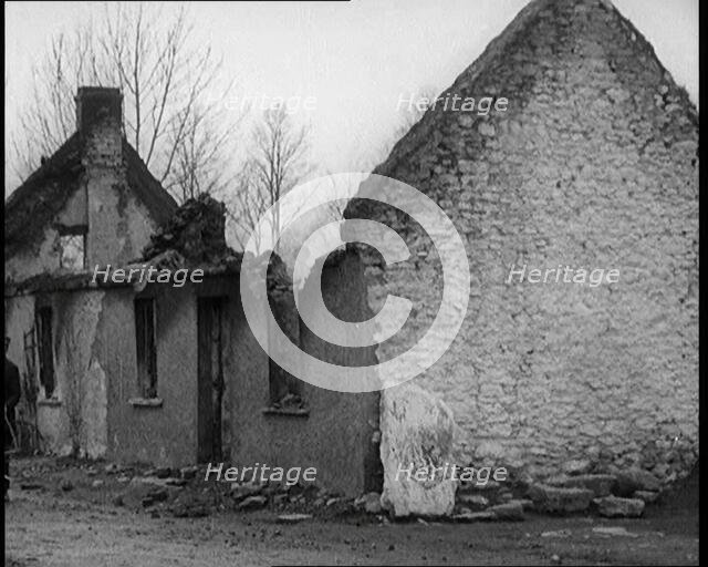 A Man Standing Outside a Burnt Out Cottage in Ireland, Holding a Bicycle, 1921. Creator: British Pathe Ltd.