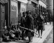 Irish Soldiers Sitting in the Street and Tending to Their Injuries from Fighting in Dublin, 1922. Creator: British Pathe Ltd.