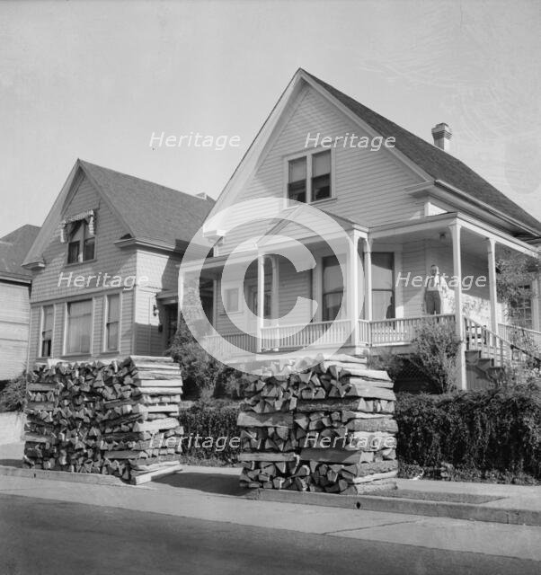 Woodpiles along the street are a characteristic of Portland, Oregon, 1939. Creator: Dorothea Lange.