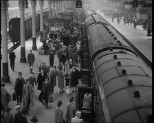 Looking Down Along a Train Platform With Passengers Walking Along, Embarking and Disembark..., 1938. Creator: British Pathe Ltd.