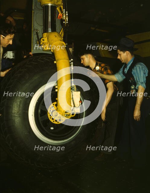 Inspecting of landing wheel of the transport planes at Willow Run, between 1941 and 1945. Creator: Howard Hollem.