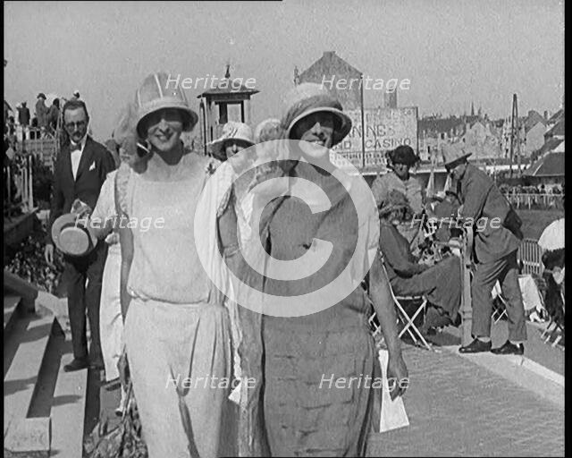 Two Female Civilians Wearing Smart Outfits Walking Towards the Camera in a Horse Race Event, 1920. Creator: British Pathe Ltd.