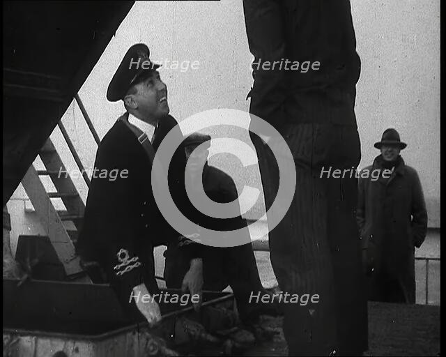 A Male Customs Official Standing by a Hatch and Talking to a Man on Board a Large Ship in..., 1939. Creator: British Pathe Ltd.