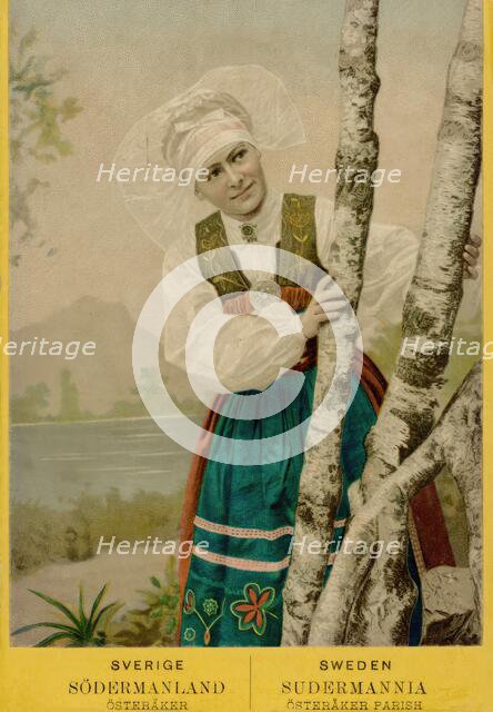 Coloured portrait photograph of a woman looking out from behind birch trunks, 1870-1900.  Creator: Unknown.