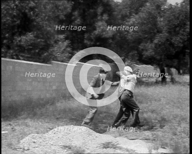 Two Male American Civilians Covering Their Faces with Handkerchiefs Carrying a Male American...1930. Creator: British Pathe Ltd.