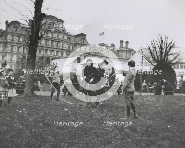 Children jumping rope on the White House lawn during annual Easter egg roll with State, War...1898. Creator: Frances Benjamin Johnston.