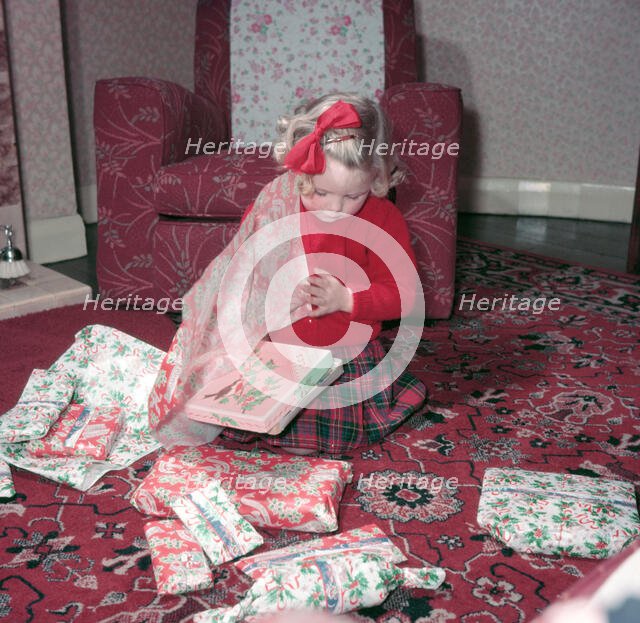 Girl opening her Christmas presents, c1955.  Creator: Arthur Charles Kirby Ware.
