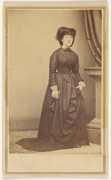 Unidentified woman wearing a hat and long dark dress, about 1868. Creator: Mathew Brady.