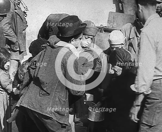 Italian Civilians Getting Assistance from American Soldiers in a Bomb-Damaged Italian Town, 1943-44. Creator: British Pathe Ltd.