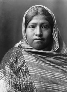 Yaqui girl, head-and-shoulders portrait, facing front, with striped shawl draped around..., c1907. Creator: Edward Sheriff Curtis.