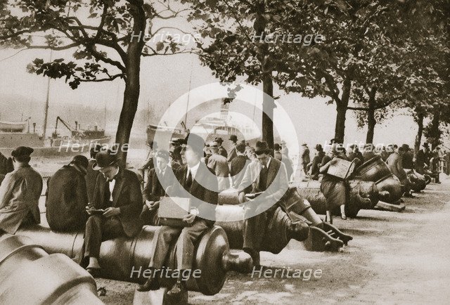 City workers lunching at Tower wharf, seated on old cannons, c1920s-c1930s. Artist: Unknown
