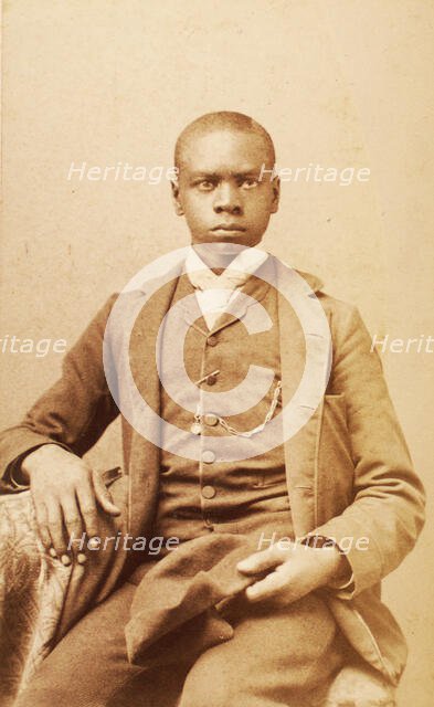 Studio portrait of unidentified seated young man, holding cap, c1880-c1889 . Creator: A. H. Plecker.