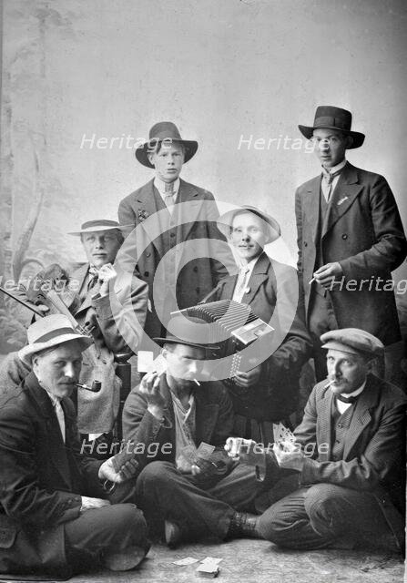Group photo of men with musical instruments and playing cards, 1915.  Creator: Unknown.