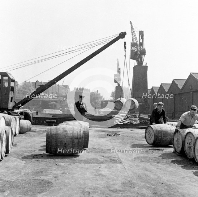 Unloading wine barrels, London Docks, 1953. Artist: Henry Grant