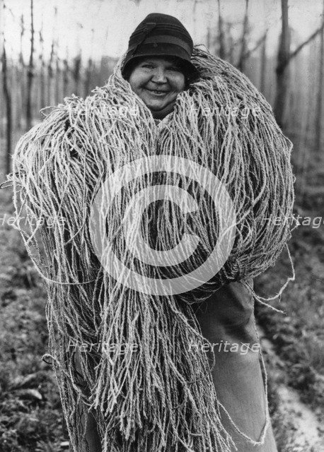 Woman carrying a large bundle of string or fibre, c1937. Artist: Unknown