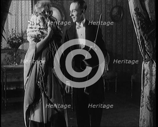 A Civilian Couple Wearing Evening Outfits Ready to Leave for an Event, the Male Holds a Top..., 1920 Creator: British Pathe Ltd.