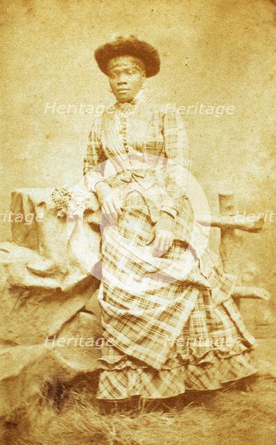 Portrait of unidentified young woman in plaid dress and hat, c1880-c1889. Creator: Thomas Gates.