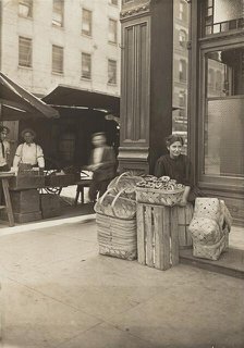 Lena Lochiavo - 11 years old, basket (and pretzel) seller, at Sixth Street Market in front of saloon Creator: Lewis Wickes Hine.