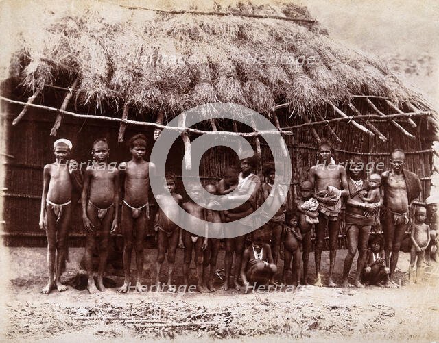 A group of adults and children standing in a line outside a bamboo hut with a thatched..., 1896/1897 Creator: Unknown.