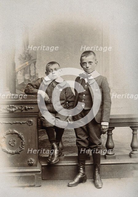 Two boys, one sitting and one standing: the former appears physically deformed, 1899. Creator: Unknown.