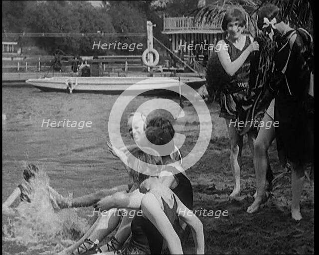 A Group of Young Female Civilians Wearing Swimsuits Playing on Riverside, 1920. Creator: British Pathe Ltd.