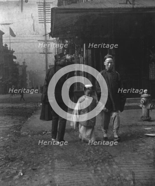 Boy and a man smoking a cigar crossing the street, San Francisco, between 1896 and 1906. Creator: Arnold Genthe.