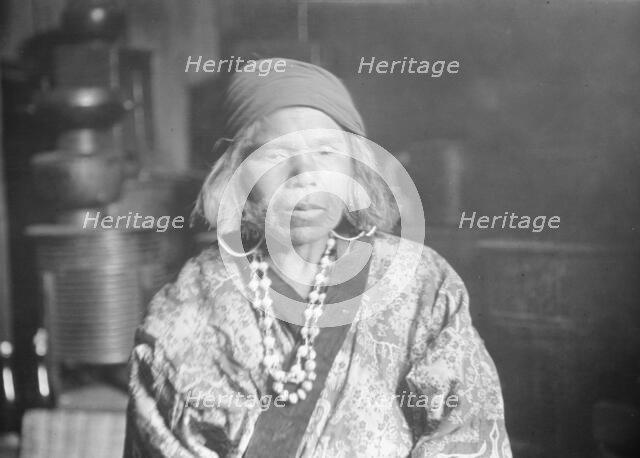 Ainu woman wearing a headscarf, earrings, and a necklace, 1908. Creator: Arnold Genthe.