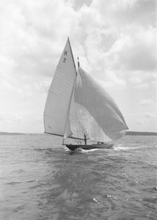 The 7 Metre yacht 'Ithnan' (K2) sailing with spinnaker, 1912. Creator: Kirk & Sons of Cowes.
