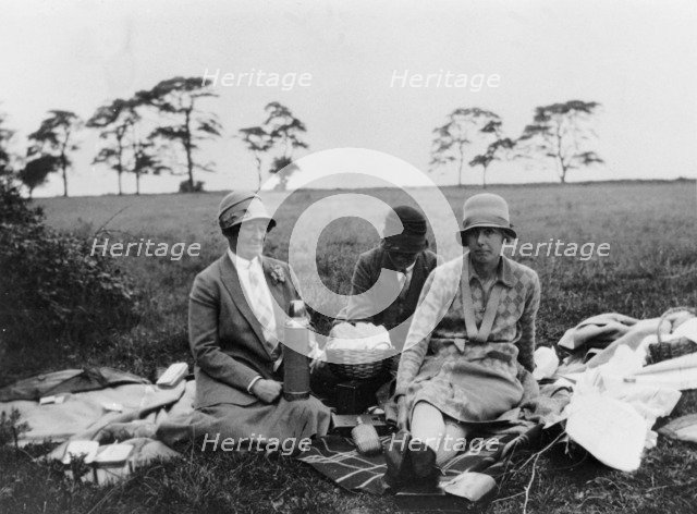 Three women having a picnic in a field, (1920s?). Artist: Unknown