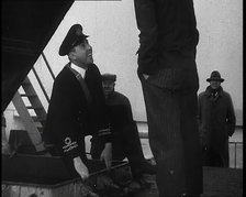 A Male Customs Official Standing by a Hatch and Talking to a Man on Board a Large Ship in..., 1939. Creator: British Pathe Ltd.