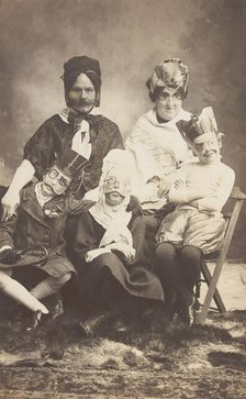 A family, all members wearing grotesque masks, the father in drag, c1910. Creator: Unknown.