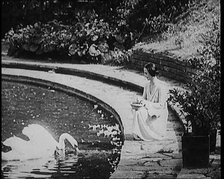 The Russian Ballerina Anna Pavlovna Pavlova Feeding Swans by a Pond, 1920. Creator: British Pathe Ltd.