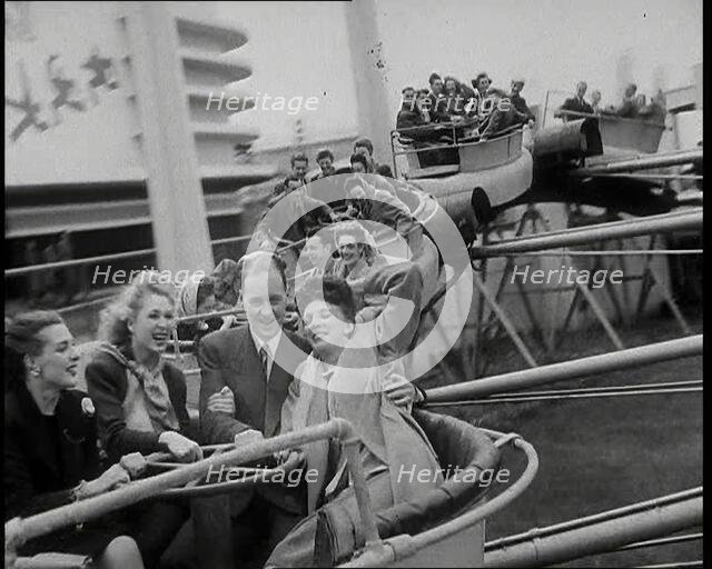 Male and Female Fairgroundgoers Riding in Gondolas Running Along Tracks on a Fairground..., 1938. Creator: British Pathe Ltd.