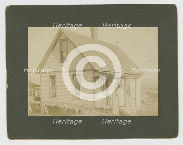 Photograph of a woman standing on the porch of a house, early 20th century. Creator: Unknown.
