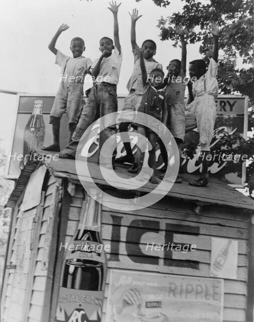 Colored boys playing on top of Coca Cola stand, Little Rock, Arkansas, 1938. Creator: Dorothea Lange.