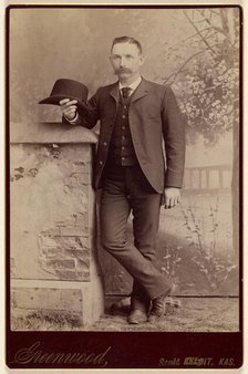 Studio portrait of a man holding a hat, about 1885. Creator: WH Greenwood.