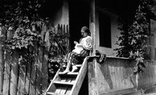 Woman sewing on her porch steps, Bistrita Valley, Moldavia, north-east Romania, c1920-c1945. Artist: Adolph Chevalier