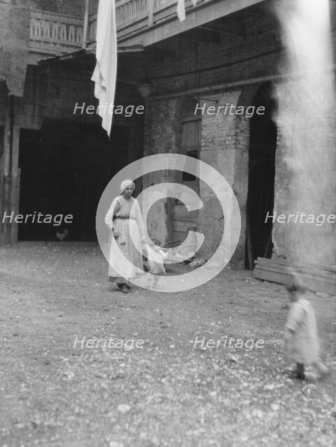 Woman and children in a courtyard, New Orleans, between 1920 and 1926. Creator: Arnold Genthe.